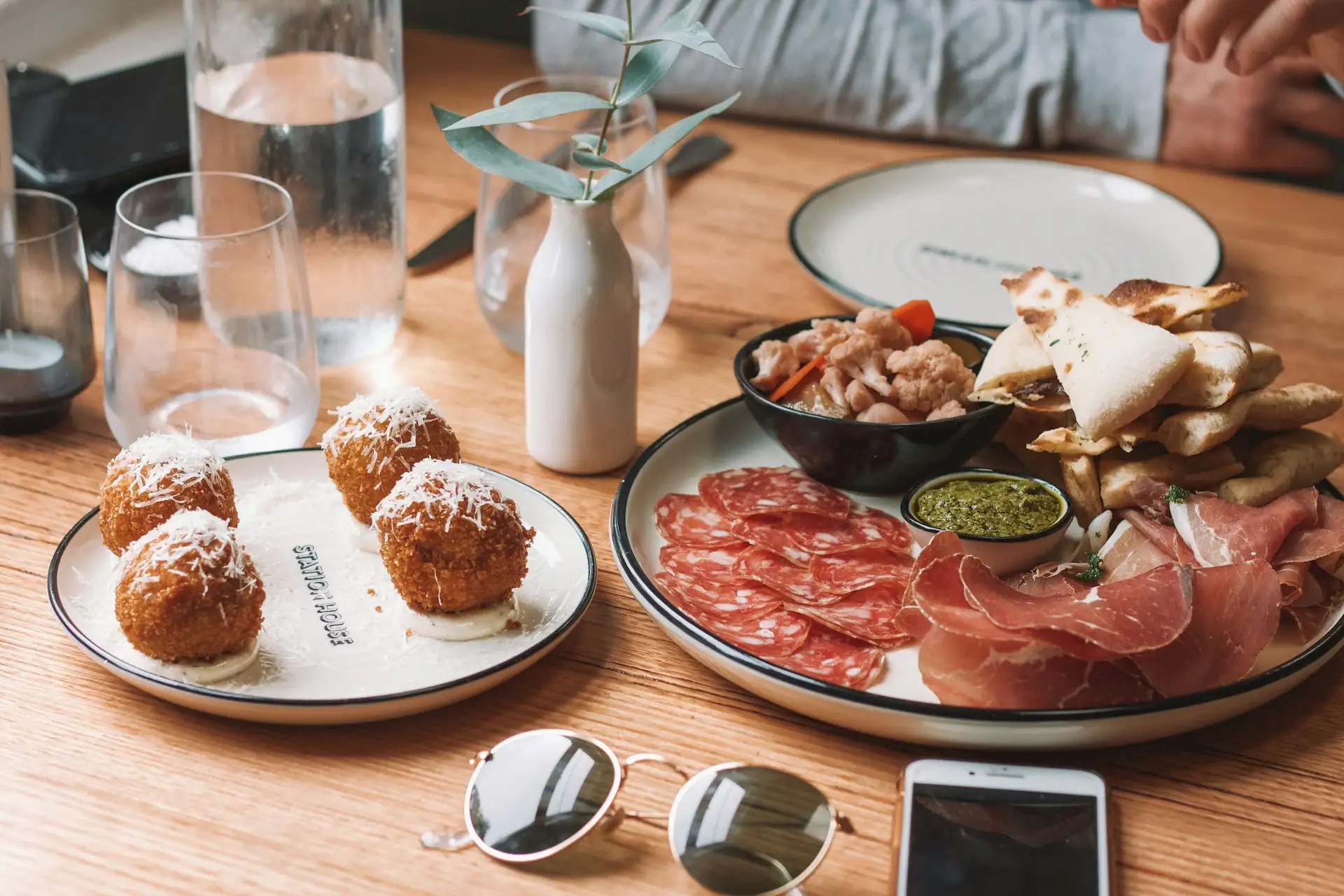 Sharing plates of charcuterie and arancini on a wooden table